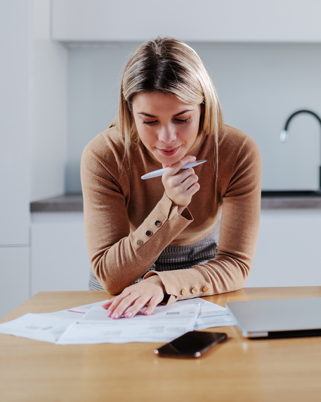 Woman looks at forms with pen in her hand