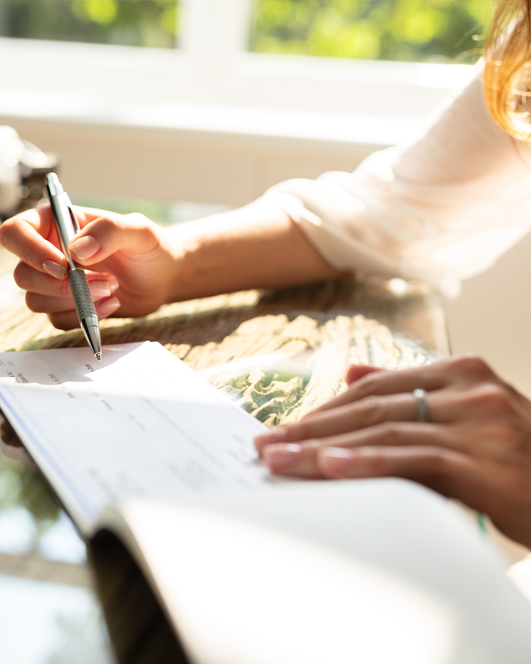 Person holding pen over checkbook