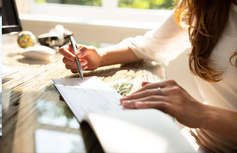 Person holding pen over checkbook