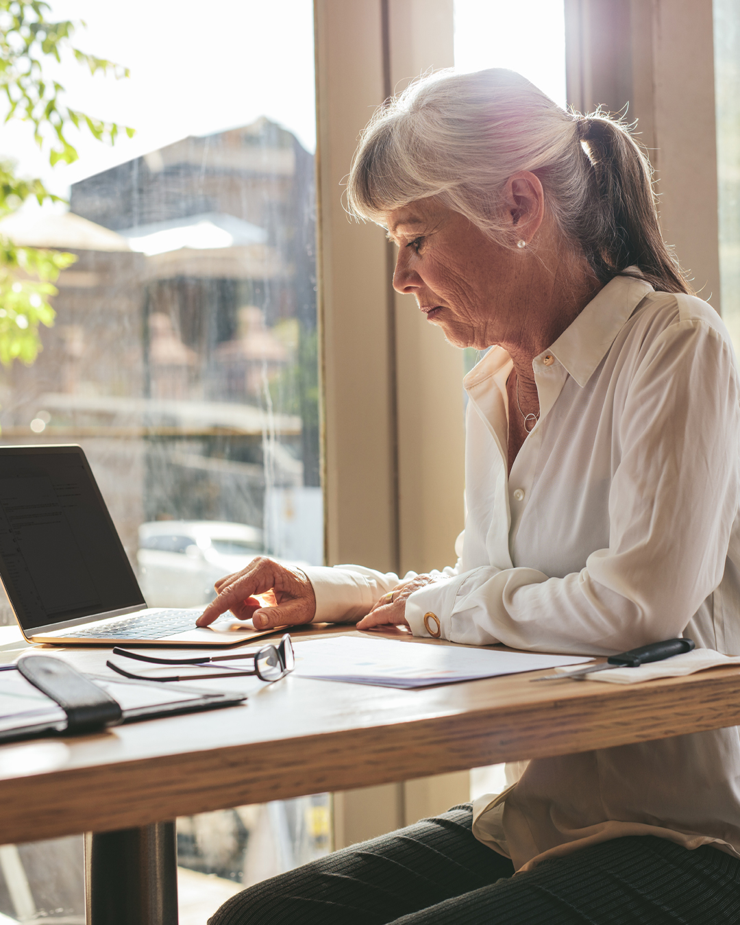 Woman looks at laptop and papers