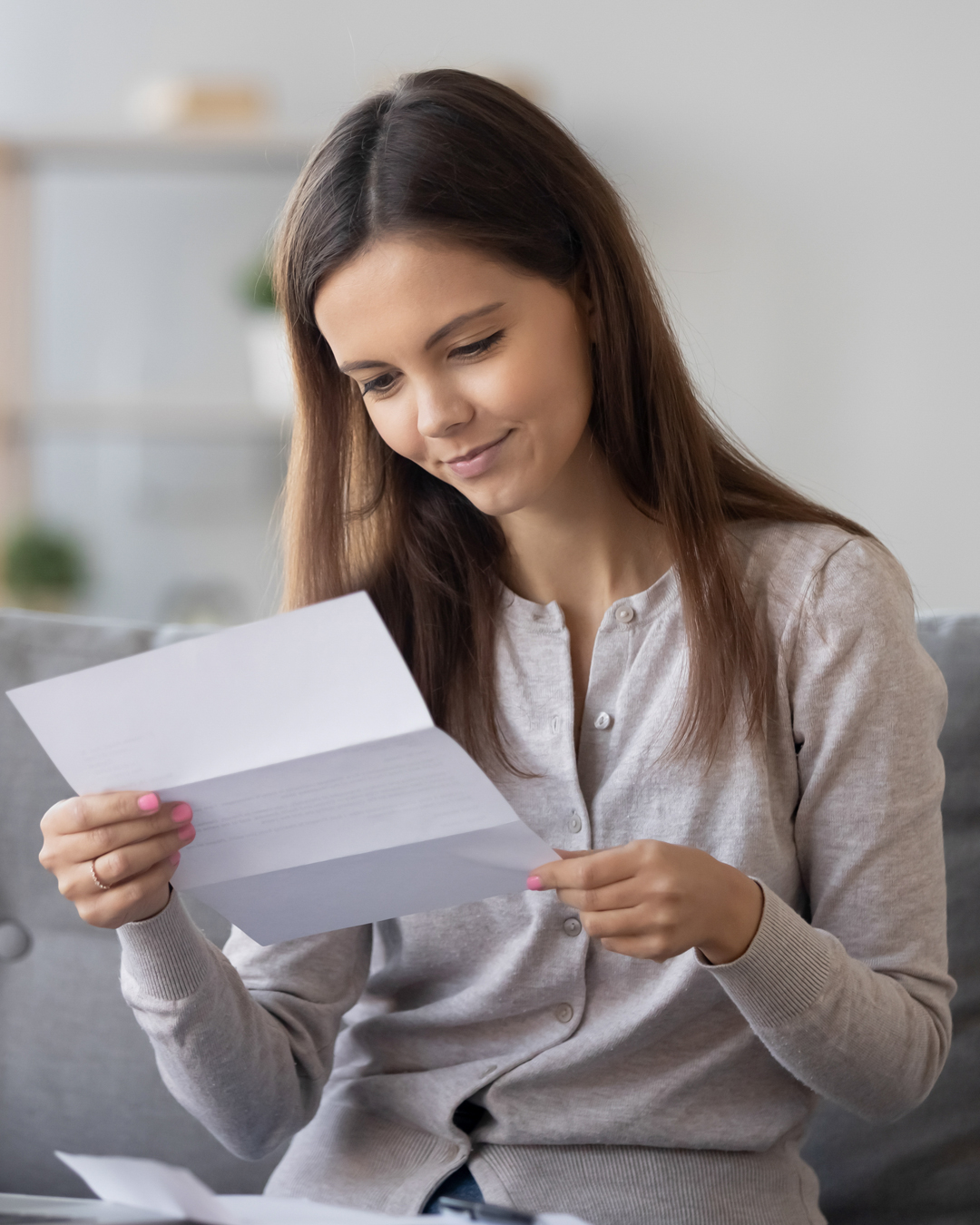 Woman smiles slightly looking at piece of paper