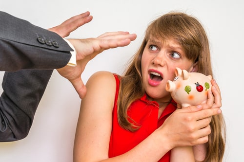 person trying to grab women's piggy bank