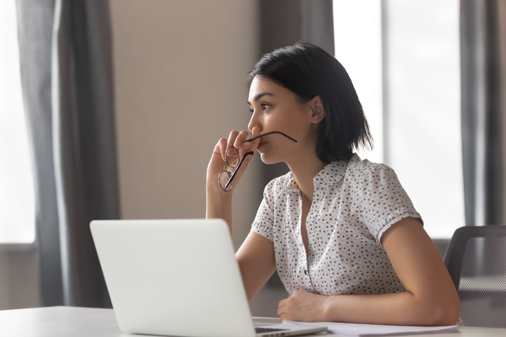 woman thinking with glasses in hands