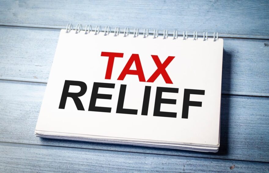 blue wooden desk with tax relief written on notepad
